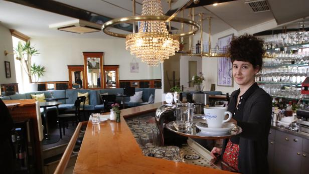 Eine Kellnerin serviert eine Tasse Kaffee in einem Wiener Caféhaus.