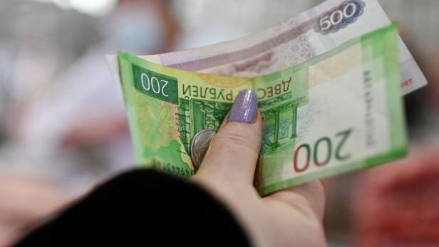 FILE PHOTO: A customer hands over Russian rouble banknotes and coins to a vendor at a market in Omsk