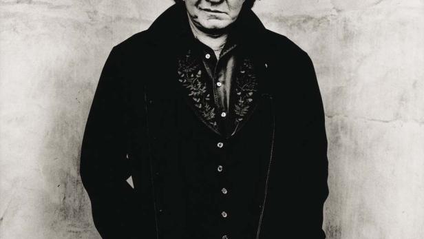 Ein Schwarzweißporträt von Johnny Cash vor einer Wand.