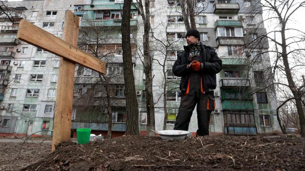 FILE PHOTO: A local resident stands next to the grave of his friend killed during Ukraine-Russia conflict in Mariupol