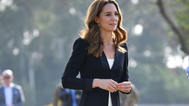 Kate Middleton trägt ein schwarzes Kleid über einem weißen Hosenanzug.