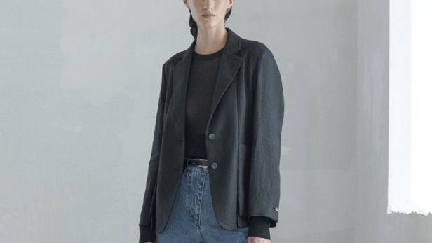 Eine Frau mit Kopftuch trägt einen Blazer und Schlagjeans mit Schlitzen.