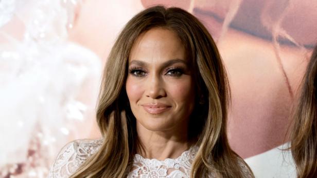 Porträt von Jennifer Lopez mit blonden Haaren und einem weißen Spitzenkleid.