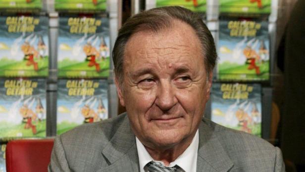 Ein Porträt von Albert Uderzo vor einer Wand mit „Asterix“-Comics.