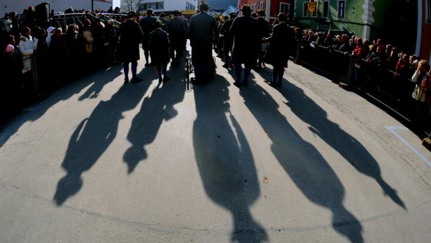 Eine Gruppe von Menschen wirft lange Schatten auf eine Straße.