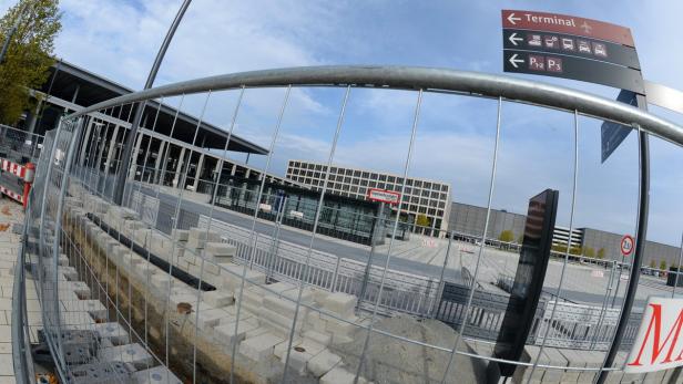 Baustelle vor dem Terminal eines Flughafens mit Hinweisschildern.