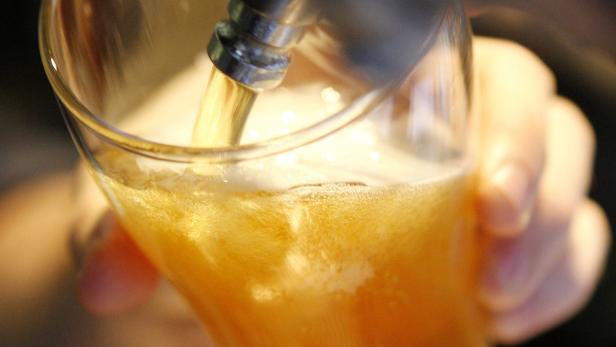 Ein Glas wird mit einem hellen, schäumenden Getränk befüllt.