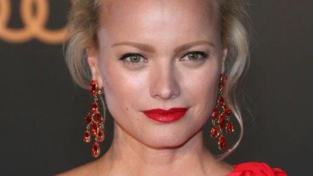 Malin Åkerman trägt ein rotes Kleid und rote Ohrringe.