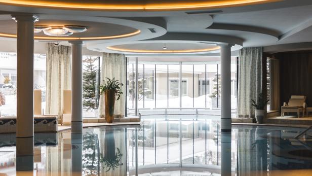 Ein Innenpool mit großen Fenstern und reflektierendem Wasser.