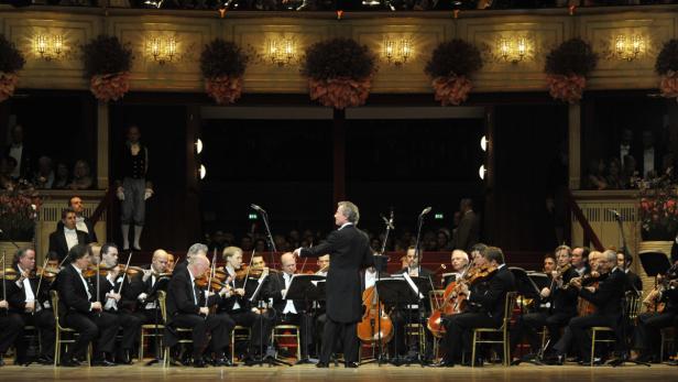 Ein Orchester spielt in einem Konzertsaal unter der Leitung eines Dirigenten.