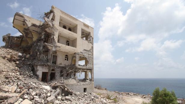 Ein zerstörtes Gebäude steht an einer Küste mit Blick auf das Meer.