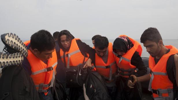 Mehrere Personen mit Schwimmwesten sitzen in einem Boot.