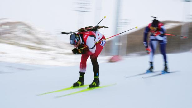 Ein Biathlet fährt auf Skiern durch den Schnee.