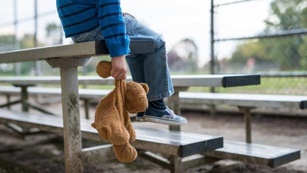 Young boy sitting by himself on on bleachers.
