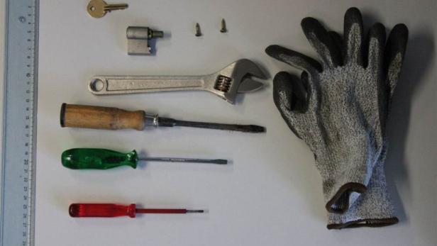 Eine Sammlung von Werkzeugen, darunter Schraubendreher, ein Schraubenschlüssel und ein Paar Arbeitshandschuhe.