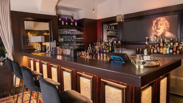 Eine Bar mit dunkler Holztheke und einem Porträt von Marilyn Monroe.