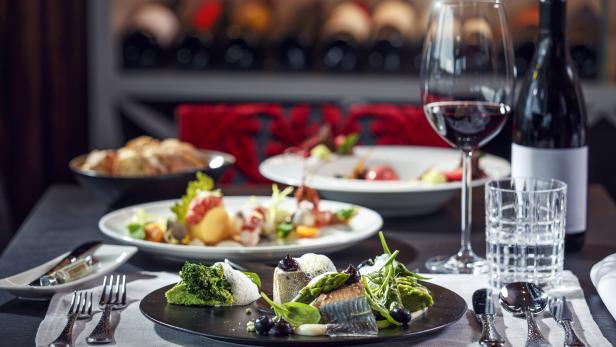 Ein gedeckter Tisch mit verschiedenen Speisen und einer Flasche Rotwein.