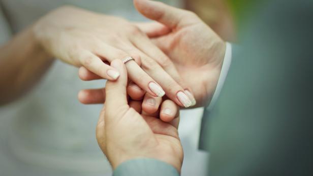 Ein Mann steckt einer Frau einen Ehering an den Finger.