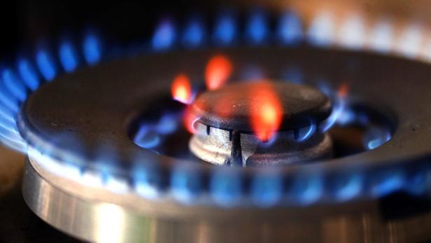 Ein Gasherd brennt mit blauer und orangefarbener Flamme auf einem Metallbrenner.