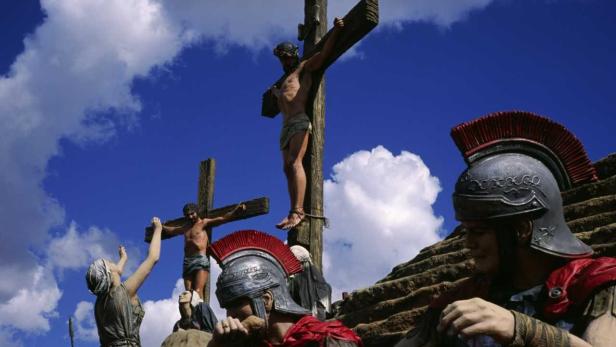 Eine Darstellung der Kreuzigung Jesu mit römischen Soldaten und Zuschauern vor blauem Himmel.