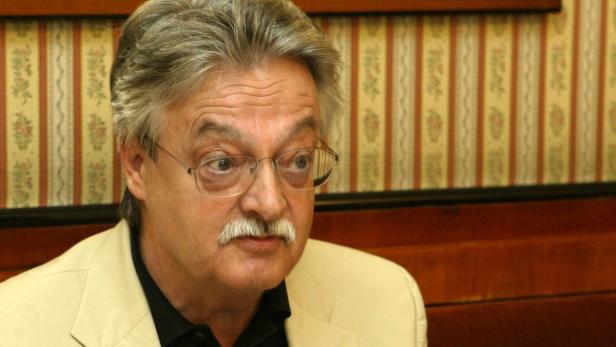 Ein Mann mit Brille und Schnurrbart blickt zur Seite.