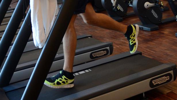 Eine Person trainiert auf einem Laufband im Fitnessstudio.