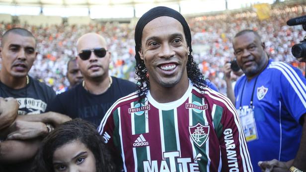 Ronaldinho posiert in einem Trikot von Fluminense Rio de Janeiro vor einer Menschenmenge.