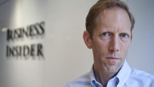 Ein Mann steht vor dem „Business Insider“-Logo.