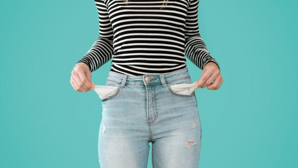Junge Frau zeigt, dass sie keine finanzielle Reserven in ihren Hosentaschen hat.