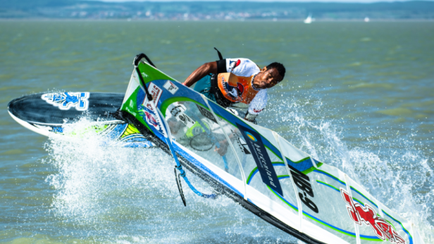 Ein Windsurfer springt mit seinem Surfbrett über das Wasser.