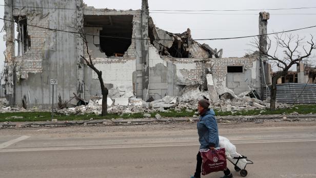 A local resident walks past a destroyed building in Mariupol