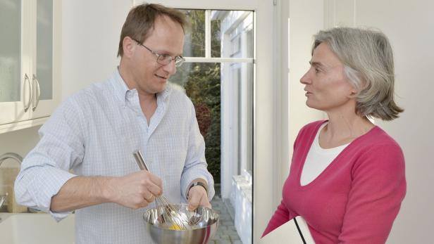 Ein Mann verrührt Eier in einer Schüssel, während eine Frau ihm zusieht.