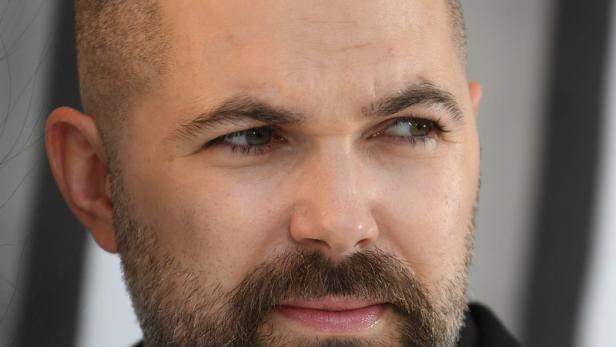 Porträt eines Mannes mit Bart und kurzem Haarschnitt, der nach rechts blickt.