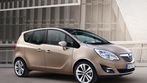 Ein goldfarbener Opel Meriva vor einer modernen Fassade.