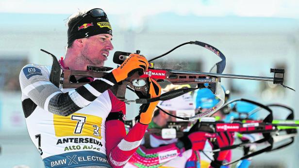 Ein Biathlet zielt mit seinem Gewehr auf eine Zielscheibe.