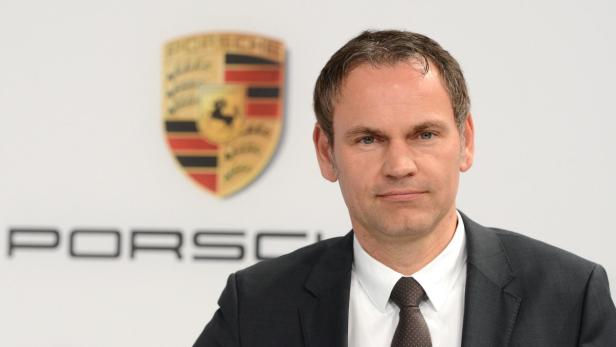 Ein Mann im Anzug vor dem Porsche-Logo.