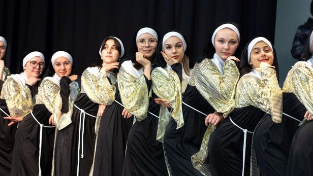 Eine Gruppe junger Frauen, verkleidet als Nonnen mit goldenen Ärmeln, posiert für ein Foto.