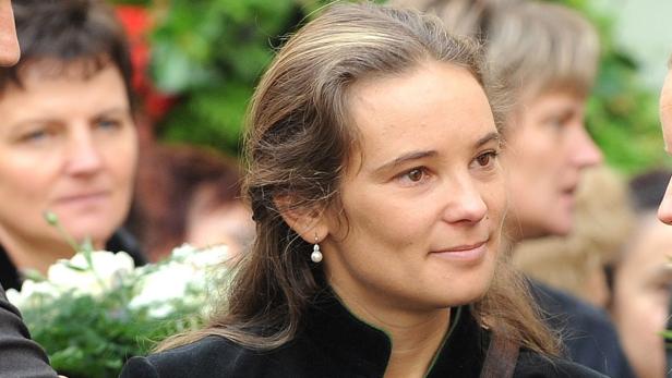 Eine Frau mit braunen Haaren und einem Ohrring mit einer Perle.