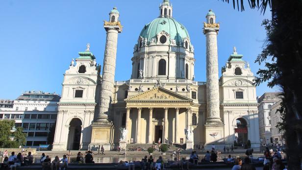 Die Karlskirche in Wien mit Menschen im Vordergrund.
