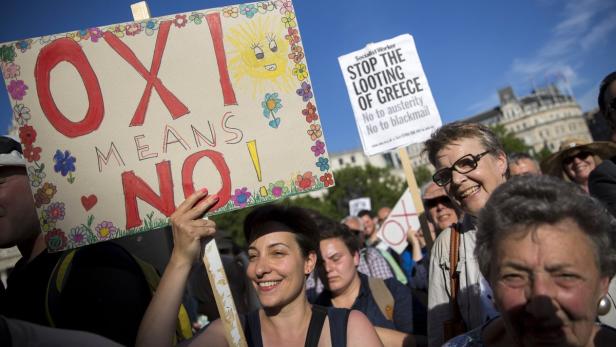 Demonstranten halten Schilder mit der Aufschrift „OXI MEANS NO!“ und „STOP THE LOOTING OF GREECE“.