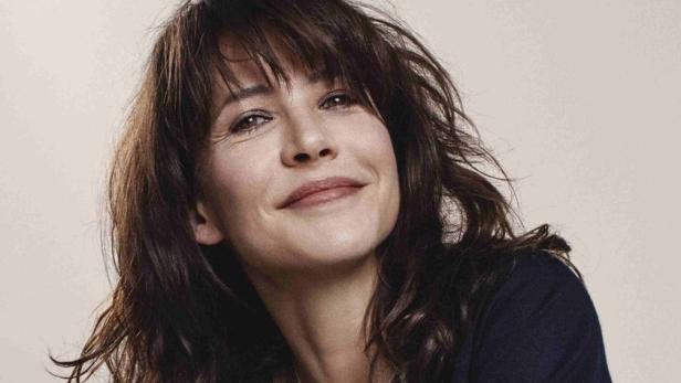 Sophie Marceau lächelt mit verschränkten Armen in die Kamera.