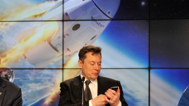 FILE PHOTO: SpaceX founder and chief engineer Elon Musk looks at his mobile phone during a post-launch news conference to discuss the  SpaceX Crew Dragon astronaut capsule in-flight abort test at the Kennedy Space Center