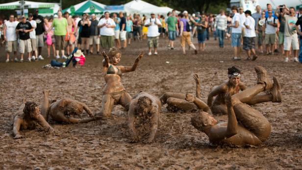 Mehrere Personen suhlen sich während eines Festivals im Schlamm.