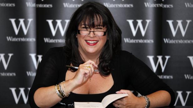 Dawn French signiert ein Buch vor einer Waterstones-Wand.