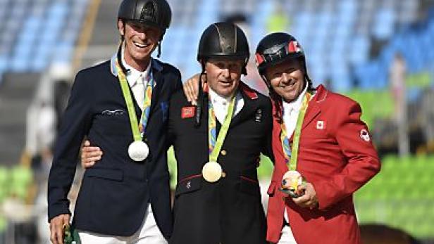 Drei Reiter mit Medaillen bei einer Siegerehrung.