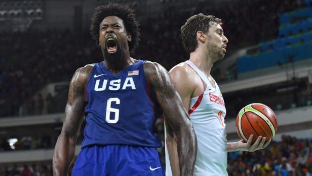 Ein US-amerikanischer Basketballspieler jubelt neben einem spanischen Spieler mit einem Ball.