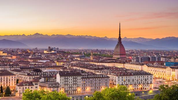 Blick auf Turin bei Sonnenuntergang mit der Mole Antonelliana und den Alpen im Hintergrund.
