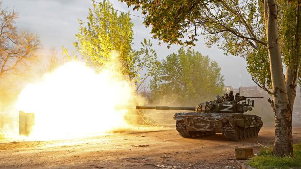 Service members of pro-Russian troops fire from a tank in Mariupol