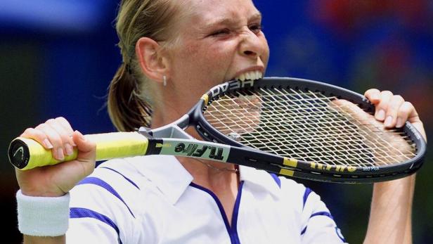 Eine Tennisspielerin beißt in ihren Tennisschläger.