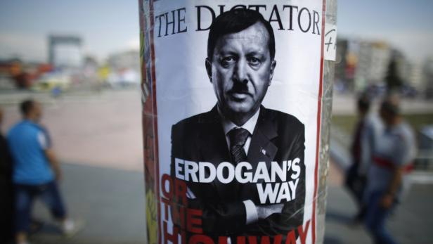 People walk past a poster depicting Turkish Prime Minister Tayyip Erdogan that has been pasted by demonstrators at Taksim Square in Istanbul June 5, 2013. Protesters clashed with police across Turkey overnight despite an apology for police violence from the deputy prime minister designed to halt an unprecedented wave of protest against Prime Minister Tayyip Erdogan. Pro-government newspapers signalled a softening of Ankara&#039;s line in the absence of Erdogan, who flew off on a state visit to north Africa on Monday night after a weekend of rioting critics said were inflamed by his denunciations of protesters. REUTERS/Stoyan Nenov (TURKEY - Tags: CIVIL UNREST POLITICS)